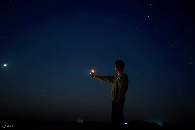 繁星点点的夜空下，一个人影手持一盏小灯——夜晚的静谧时刻。