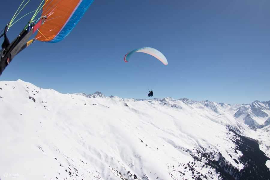 Experience paragliding amidst the Swiss Alps blanketed in pristine snow, savoring the breathtaking wintry vistas below