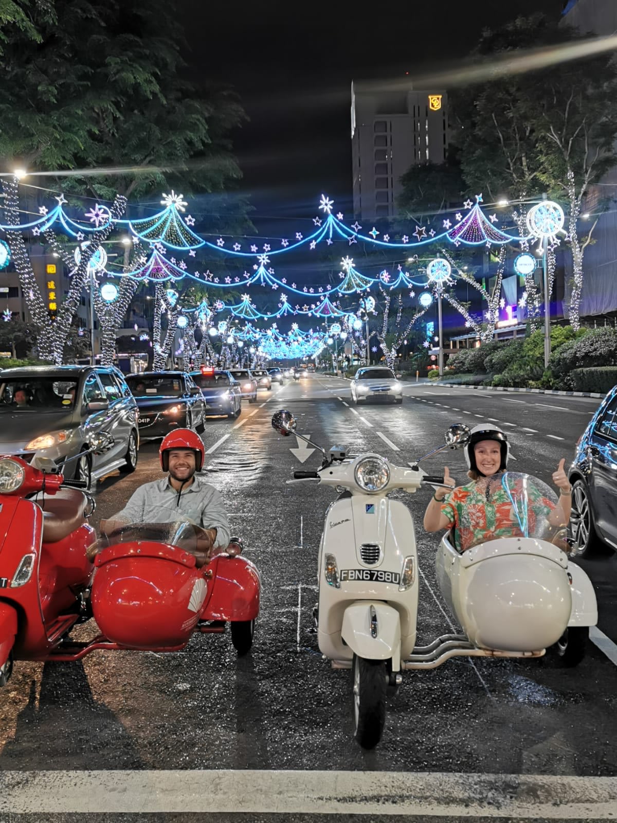 Two riders in a vintage Vespa sidecar on a Singapore street