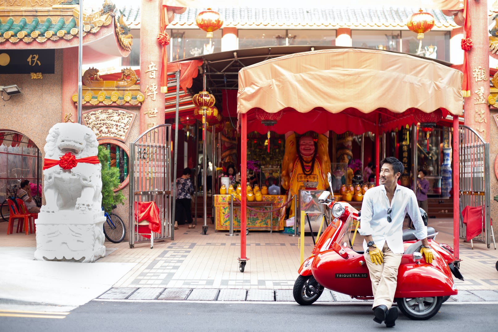 Driver standing beside a vintage Vespa sidecar on a Singapore street